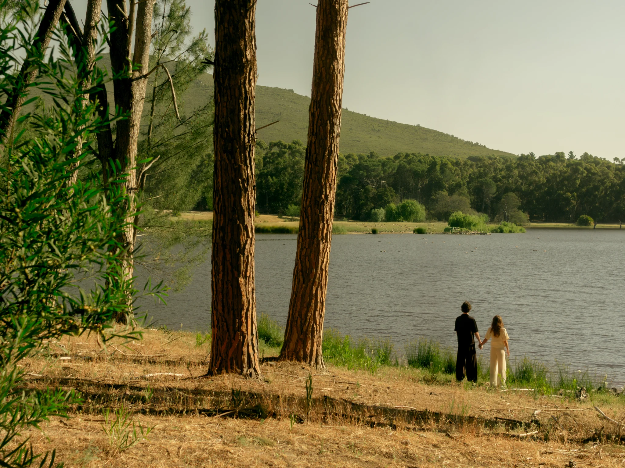 Two people standing together by a lake